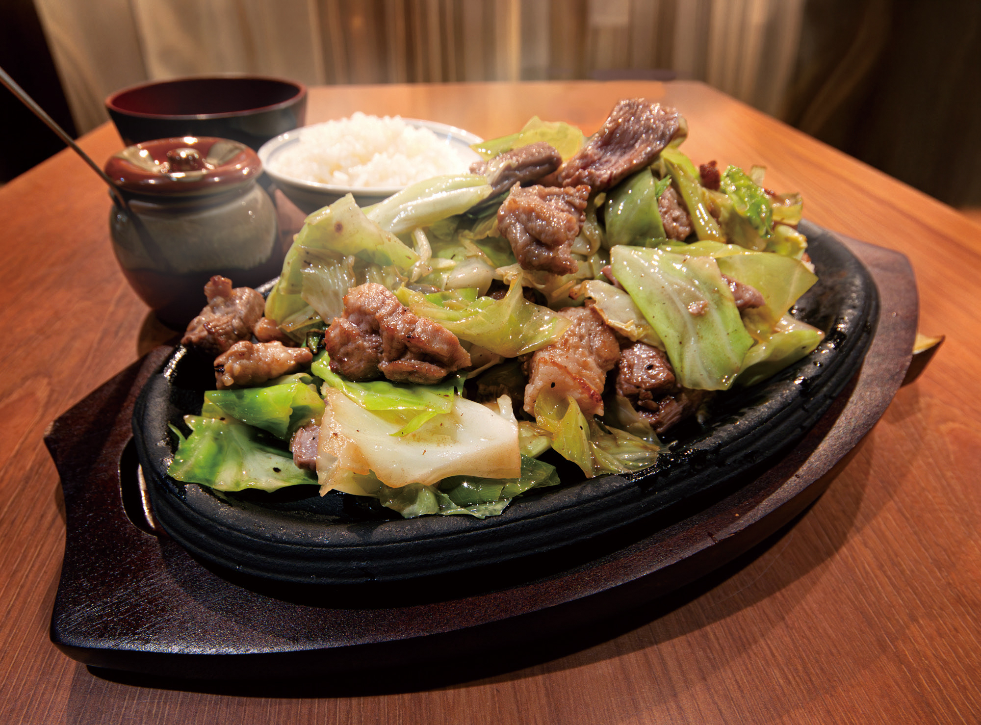 熱々の鉄板に盛り付けた焼肉とキャベツ、ご飯と味噌汁